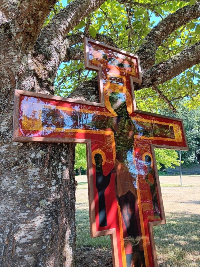 painted cross leaning on a tree