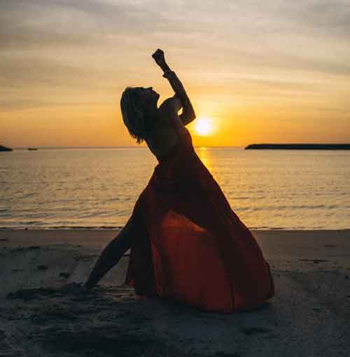 A Woman in Red Dress Dancing on the Beach during Sunset<br />
