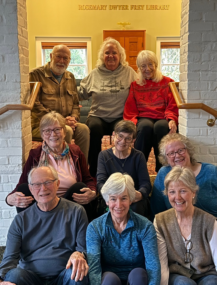 Group of smiling people posing for a photo sitting in a stone doorway on the stairs