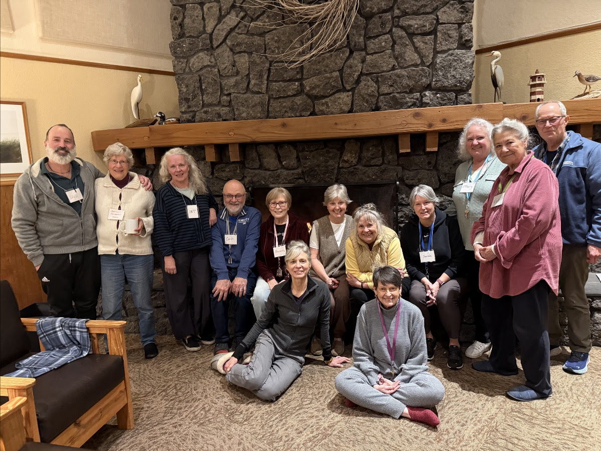 Group picture of attendees in front of a stone fireplace. 