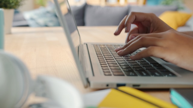 Hands of an unseen person typing on a laptio