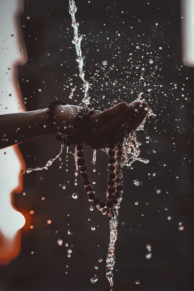 hands being washed while holding prayer beads