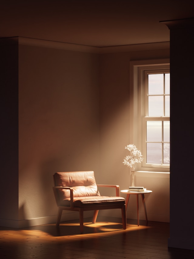 leather chair and table with flowers by a window in a dark room with a sun beam resting on the chair 